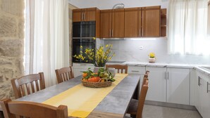 Une cuisine avec des meubles de rangement en bois, une table à manger avec des chaises et un vase rempli de fleurs.
