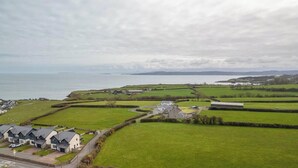 A coastal village with houses, a road, and fields.
