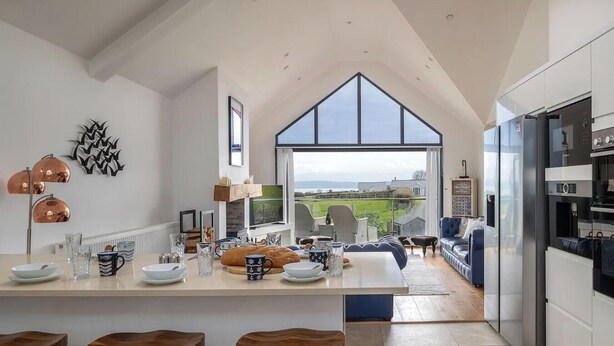 A modern kitchen with a large island, a dining area, and a view of the countryside.