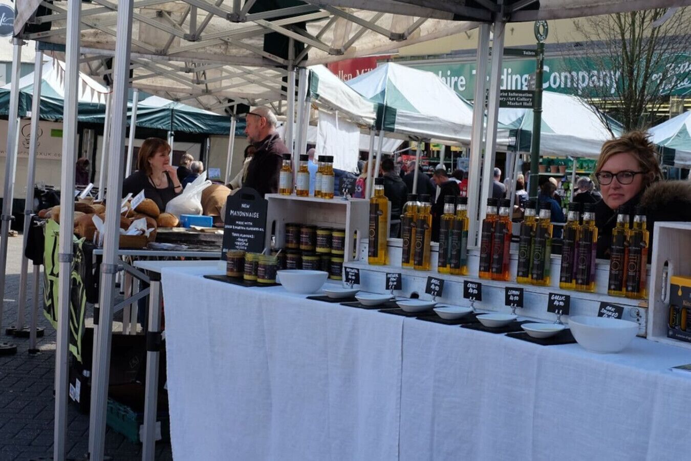 Un puesto de mercado con varios productos expuestos sobre mesas, incluyendo botellas y frascos.