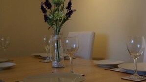 A dining table set with plates, glasses, and a vase with flowers.