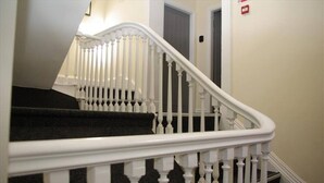 Un escalier avec des balustrades blanches et une main courante recouverte d’un tapis noir.