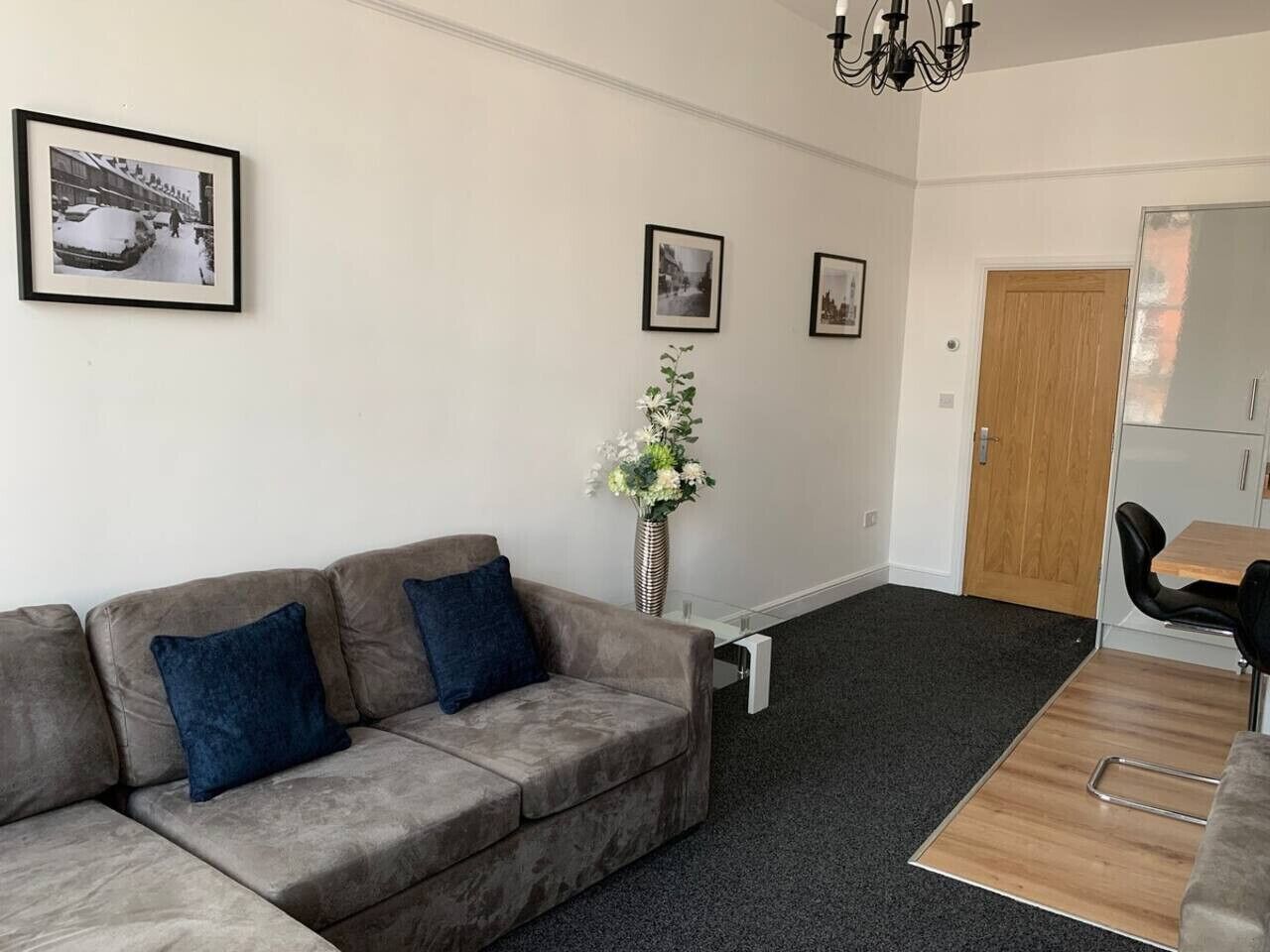 A living room with a sofa, a dining table, and a vase of flowers.