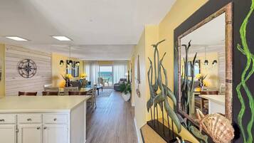 A spacious living area with a large island, a dining area, and a view to the outside.