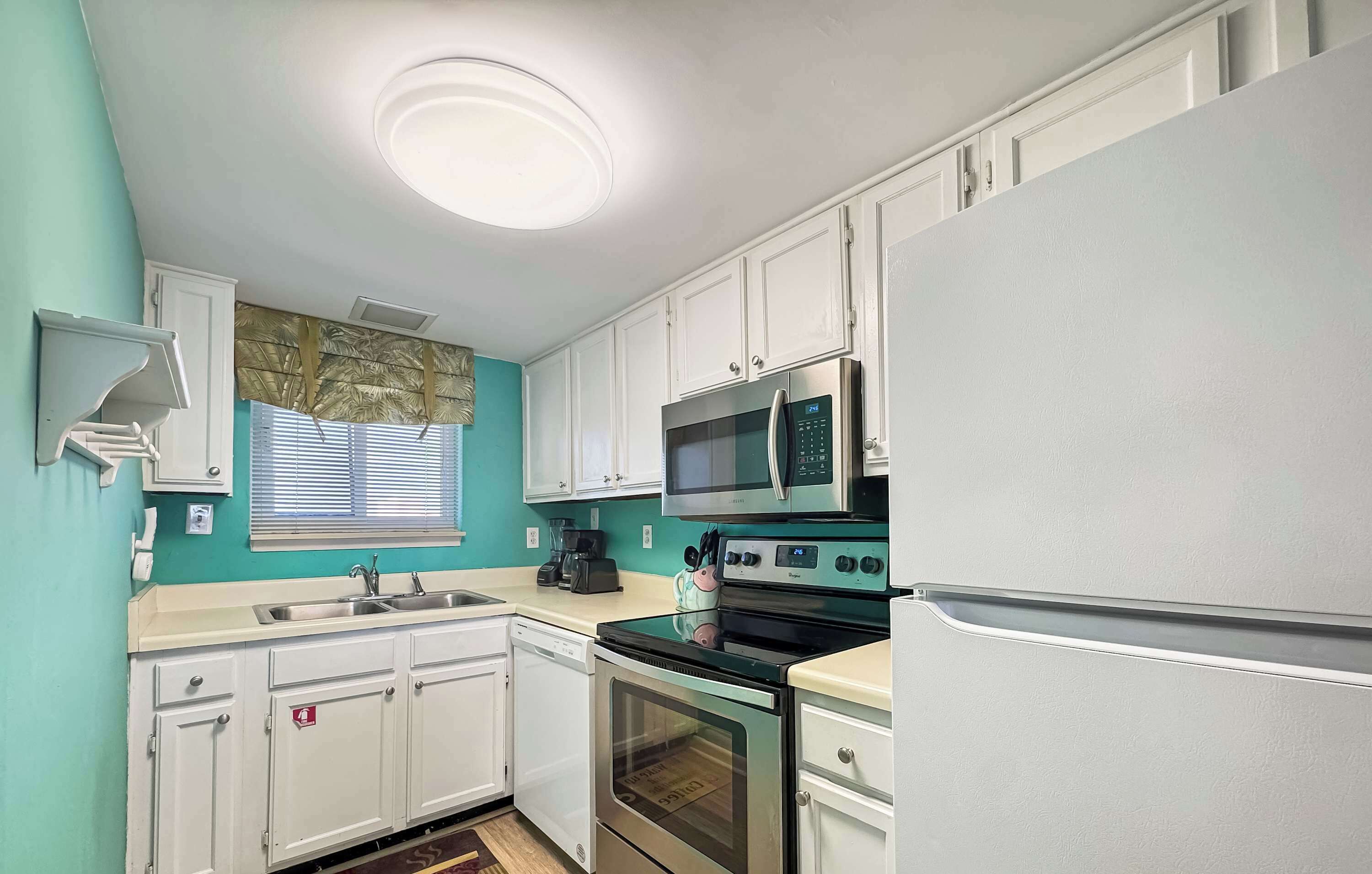 A kitchen with white cabinets, a microwave, an oven, and a refrigerator.