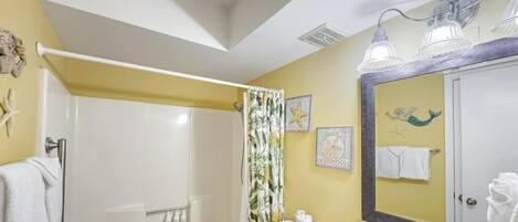 A bathroom with a shower, toilet, sink, and a large mirror.
