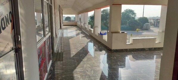 Corredor com piso espelhado, balcão de recepção e vista para o exterior.