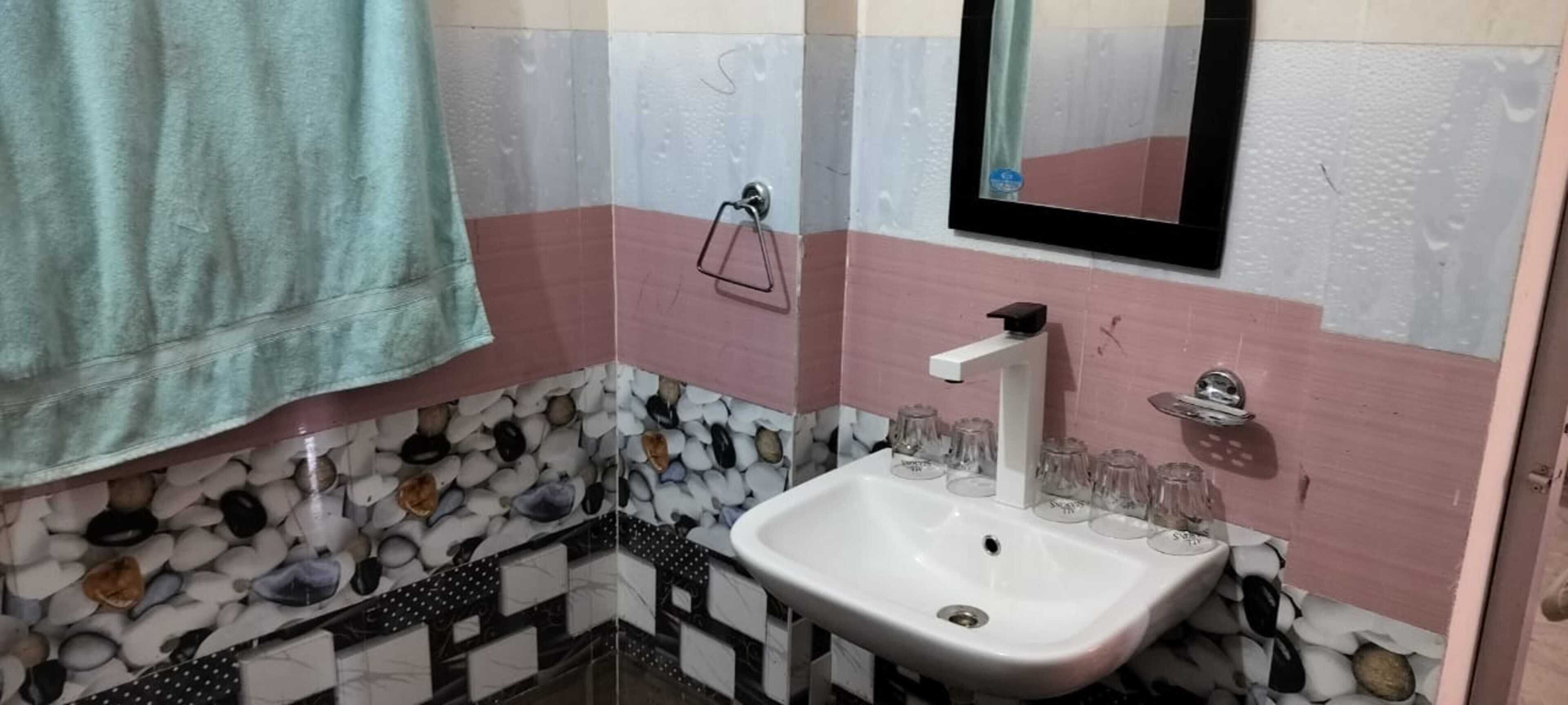 Un bagno con lavandino, specchio e porta asciugamani.