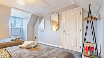 A hotel room with two beds, a large mirror, a door, and a hanging chair.