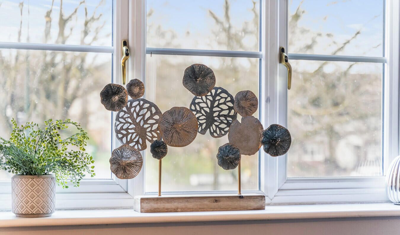 A window with decorative metal art pieces and a potted plant on a windowsill.