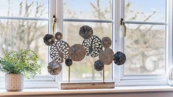 A window with decorative metal art pieces and a potted plant on a windowsill.