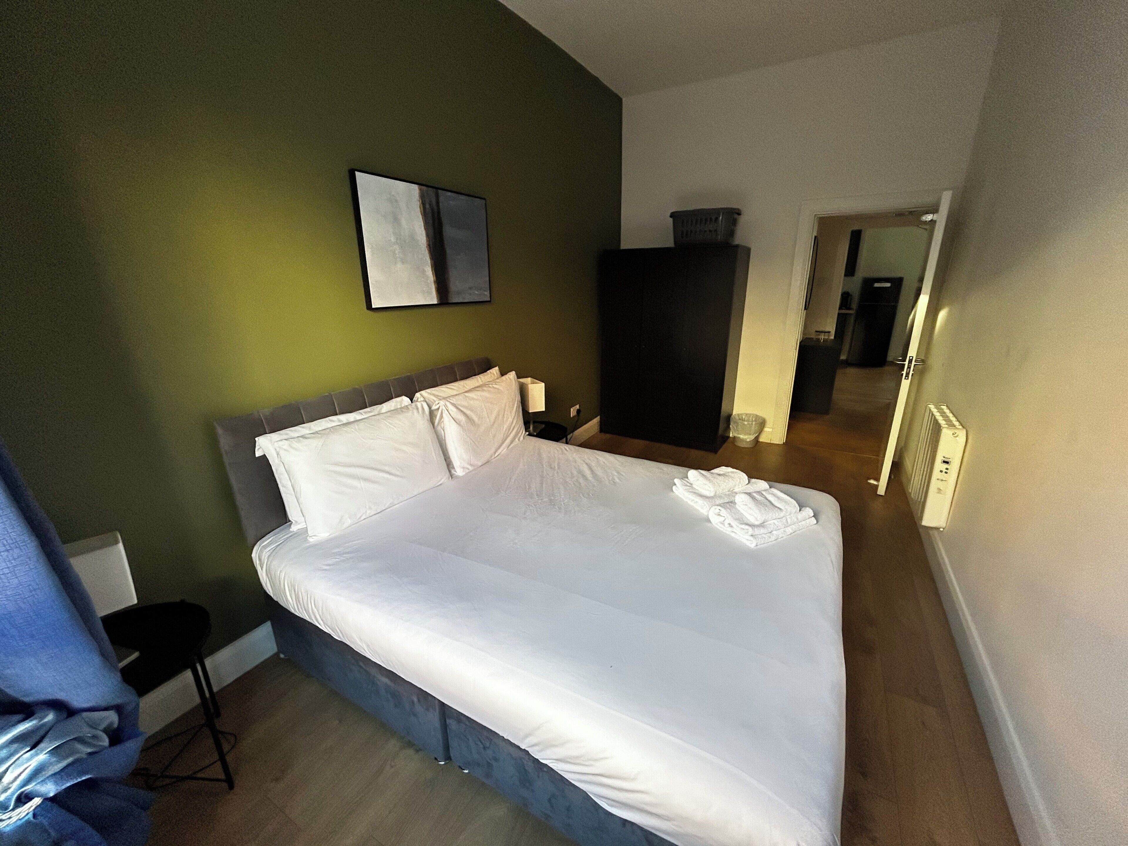 Une chambre d’hôtel avec un lit, une chaise, une armoire et un miroir.