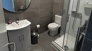 Un baño moderno con lavabo, inodoro y ducha con cerramiento de vidrio.