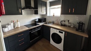 Cocina compacta con lavavajillas, horno, microondas y una ventana sobre el fregadero.