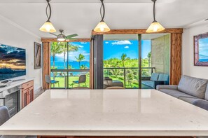Ein geräumiges Zimmer mit großem Esstisch, einer Couch und Blick aufs Meer.
