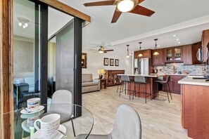 A modern kitchen with a central island, bar stools, and wooden cabinets. - Kihei Surfside #512: Luxe Oceanfront Escape with Gorgeous Views! (Kihei, Maui)