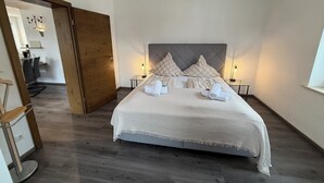A hotel room with a large bed, two bedside tables, a wooden door, and a view of the hallway. - Vacation apartment Marienplatz (Garmisch-Partenkirchen)