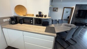 A modern kitchen with built-in appliances, a wooden countertop, and a dining area with a sofa and chairs. - Vacation apartment Marienplatz (Garmisch-Partenkirchen)