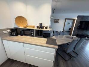 A modern kitchen with built-in appliances, a wooden countertop, and a dining area with a sofa and chairs. - Vacation apartment Marienplatz (Garmisch-Partenkirchen)