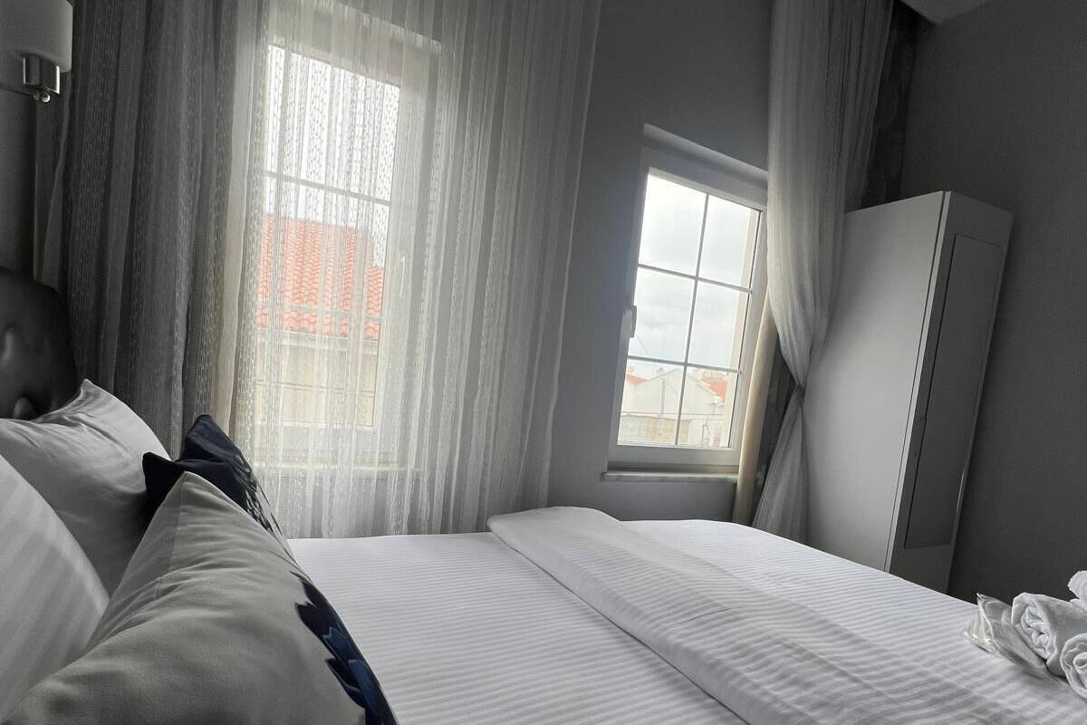 A hotel room with a bed, a wardrobe, and a window with curtains.