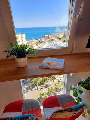 A room with a view of the sea, a potted plant, a starfish book, and two chairs with a patchwork design. - Exclusive Designer Apartment | Stunning Sea Views & Walk to Beach (Benalmádena)