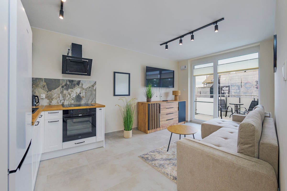 A modern kitchen with a built-in oven, a wooden countertop, and a large window.