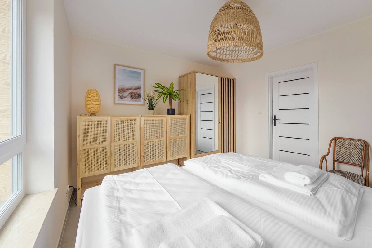 A bedroom with a bed, a wardrobe, a hanging light fixture, and a window.