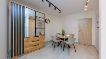 Un coin repas avec une table en bois, quatre chaises, une horloge et un miroir.