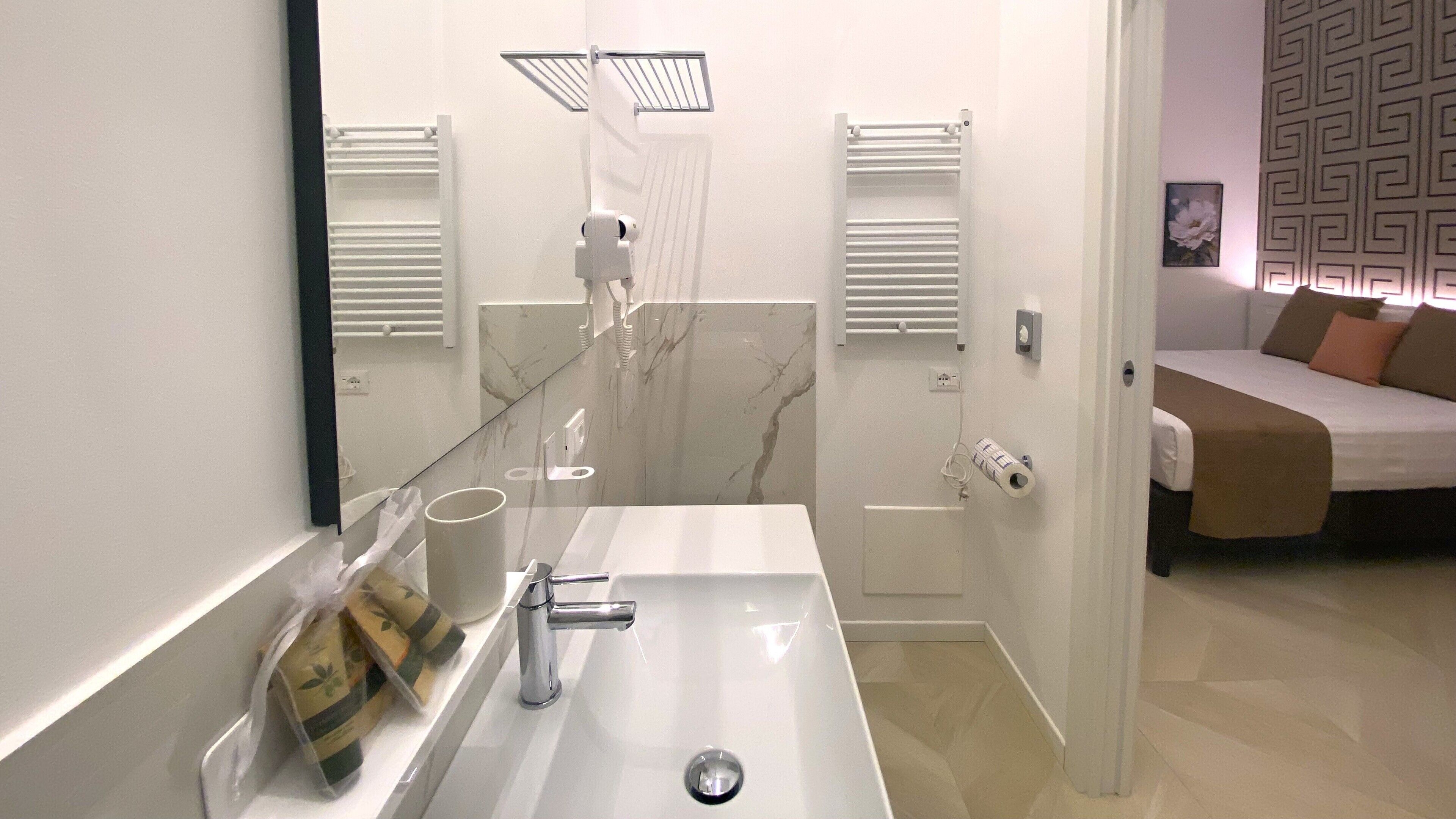 A modern bathroom with a large mirror, a white sink, and a shower area.