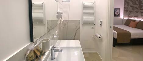Un baño moderno con un espejo grande, un lavamanos blanco y una zona de ducha.