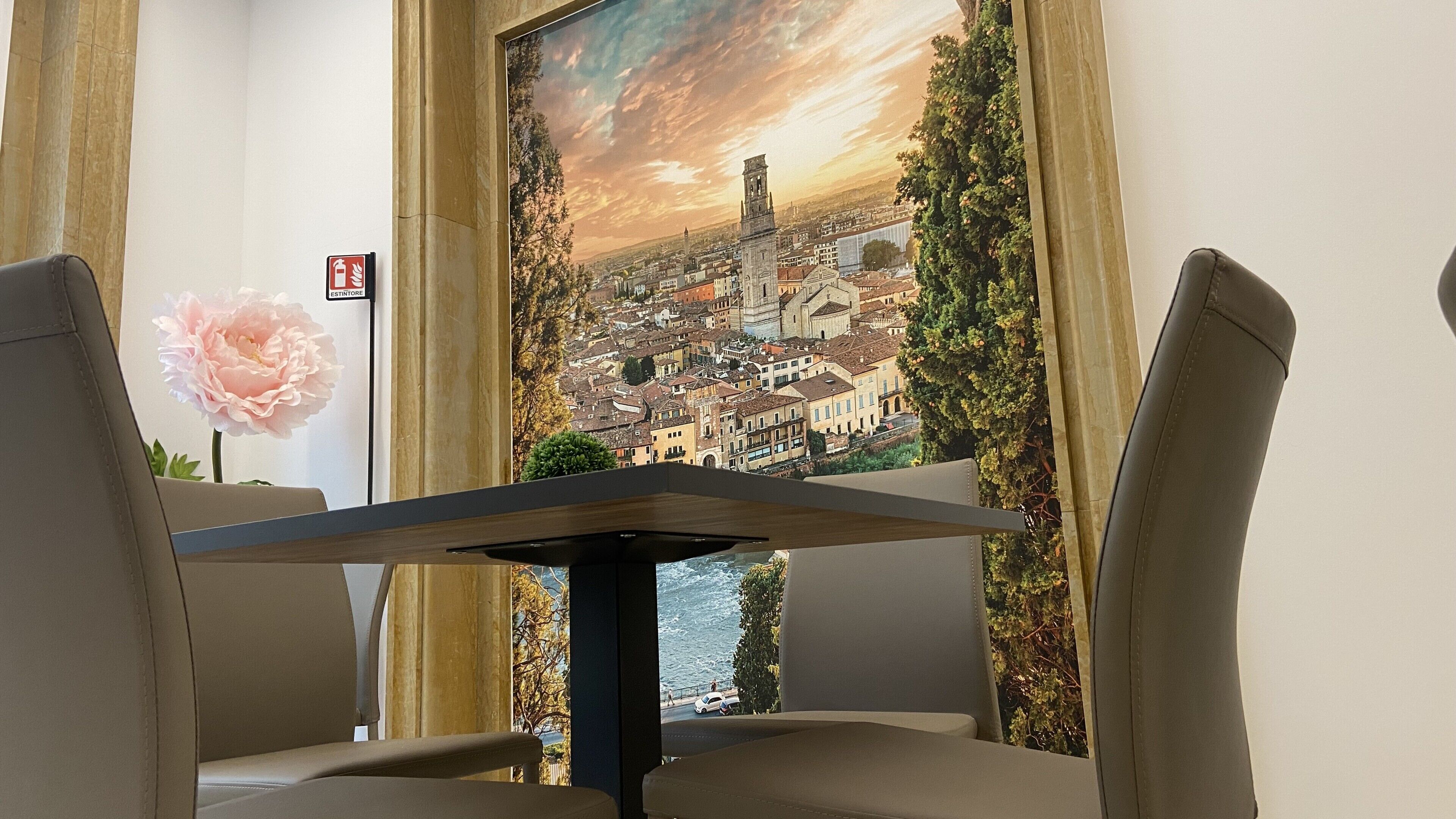 Un comedor con una mesa y sillas, un cuadro grande con una vista urbana y un letrero de salida de incendios.