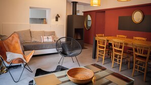 Ein modernes Wohnzimmer mit einer Couch, einem Esstisch mit Stühlen, einem Kamin und einem Spiegel an der Wand.
