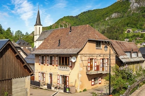 A traditional European building with a steep roof, a visible bell tower, and a balcony with a railing.