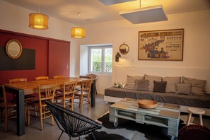 Un coin repas comprenant une table et des chaises en bois, un canapé, une table basse et un miroir fixé au mur.