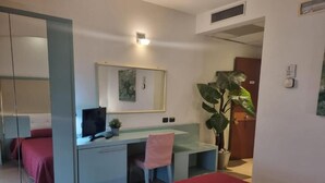 A hotel room with a bed, a desk with a computer, a chair, a large plant, and a mirror. - Affittacamere e Ristorante Ariete (Ponsacco)