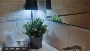 A bathroom with a white sink, a potted plant, a mirror, and a black lamp. - Affittacamere e Ristorante Ariete (Ponsacco)