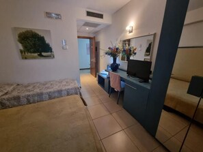 A compact living space with a bed, a desk, a TV, and a mirror. - Affittacamere e Ristorante Ariete (Ponsacco)