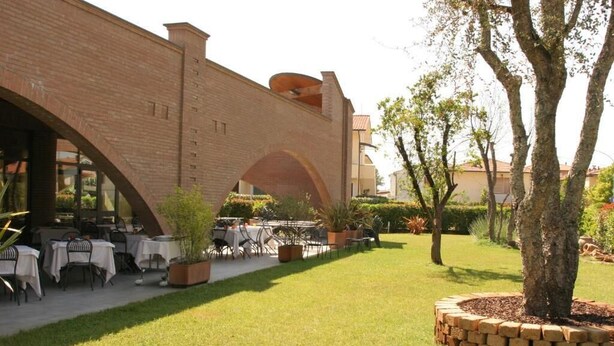 A courtyard with outdoor seating, a brick building, and a tree. - Affittacamere e Ristorante Ariete (Ponsacco)
