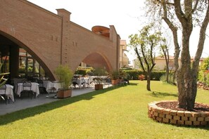 A courtyard with outdoor seating, a brick building, and a tree. - Affittacamere e Ristorante Ariete (Ponsacco)