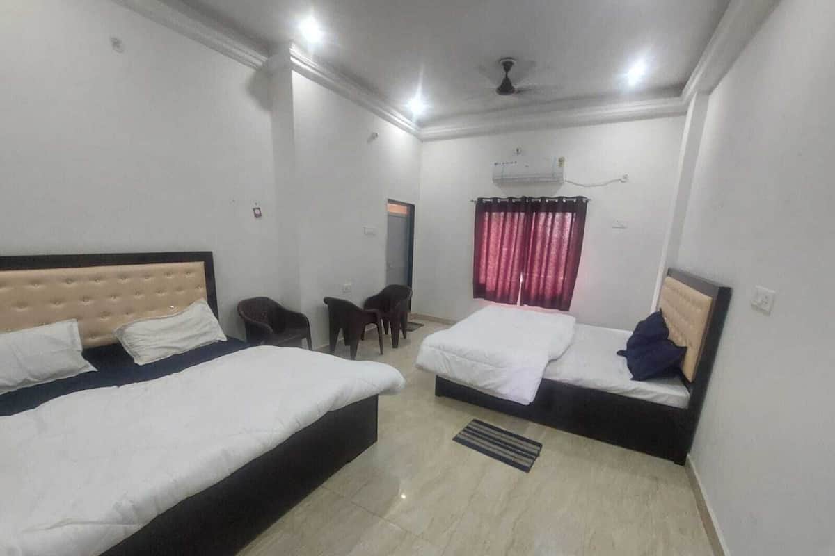 Une chambre d’hôtel avec deux lits, un ventilateur de plafond, une fenêtre avec des rideaux rouges et une petite table avec des chaises.