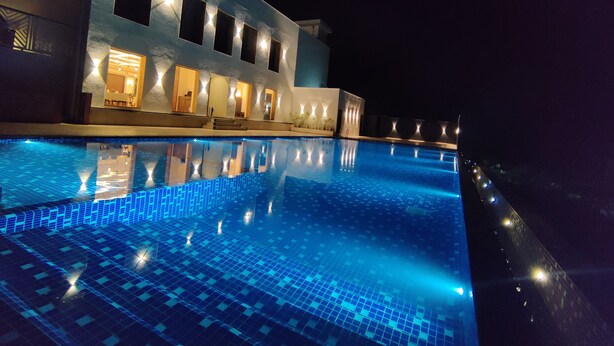 A nighttime view of a modern building with a swimming pool.