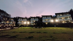 A multi-story building with illuminated windows and a well-maintained lawn.