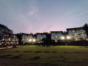Un edificio de varios pisos con ventanas iluminadas y un césped cuidado.