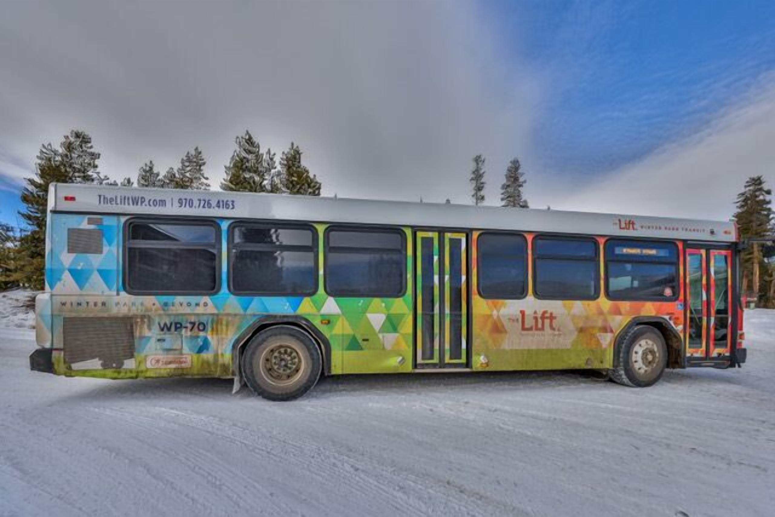 A bus with 'Lift' branding, a contact number, and 'Winter Park Beyond' text, parked in a snowy area.