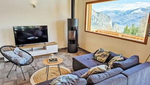 Ein modernes Wohnzimmer mit Fernseher, Sofa, Sessel und Kamin.