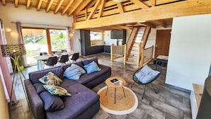 Ein modernes Interieur mit Holzboden, einer Couch, einem Essbereich und einer Treppe.