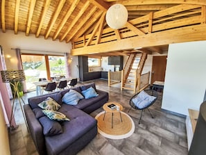 Ein modernes Interieur mit Holzboden, einer Couch, einem Essbereich und einer Treppe.