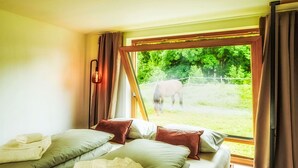 Una stanza con due letti, una finestra che dà su un cavallo e un lampadario.