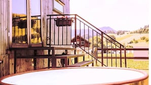 Edificio termale in legno con vasca idromassaggio, terrazza in legno e vista sul paesaggio.