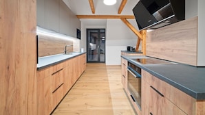 A modern kitchen with wooden cabinetry, a built-in oven, and a flat-screen TV mounted on the wall.